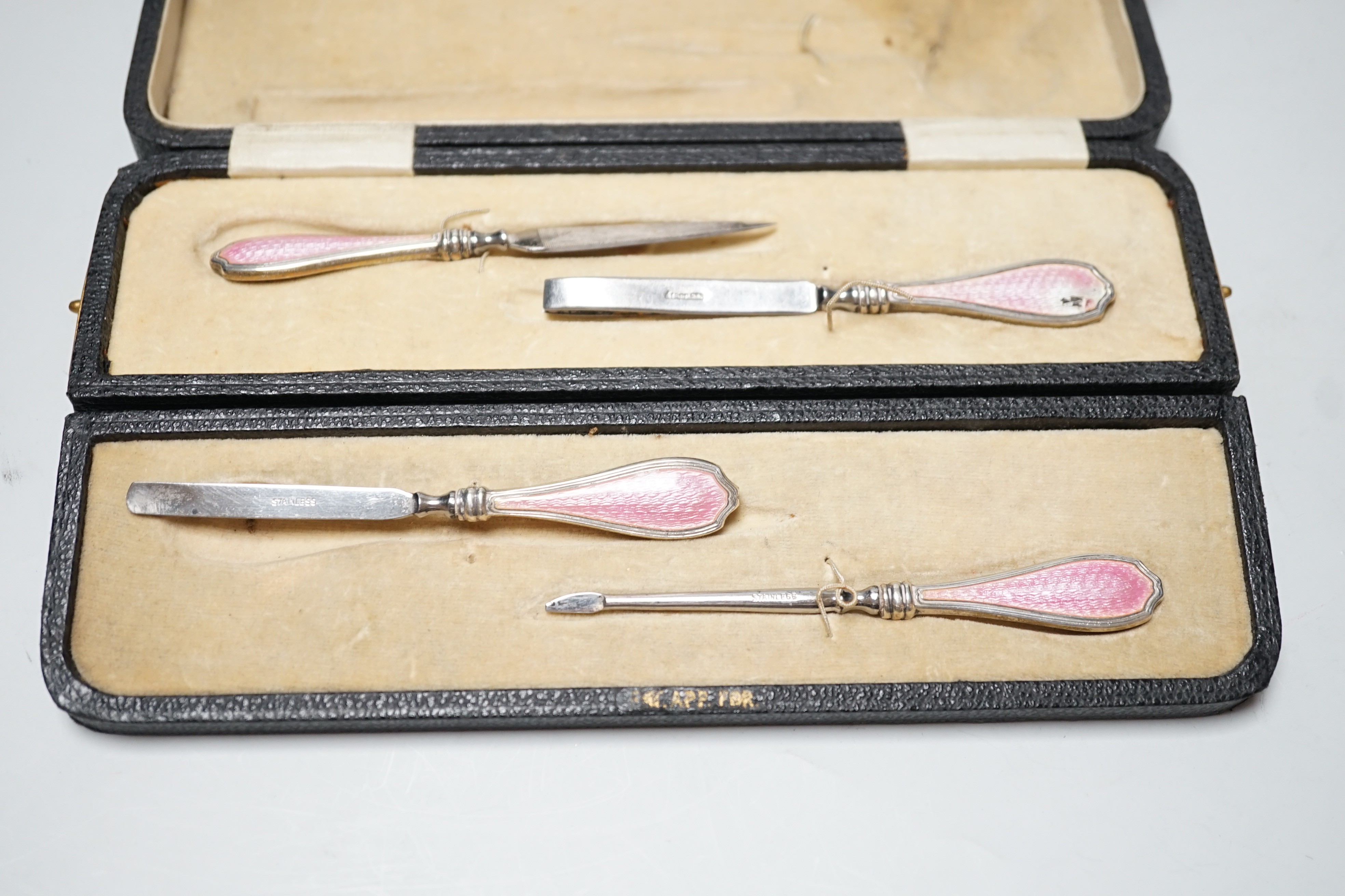 A cased George V nine piece silver and pink enamel mounted manicure set.